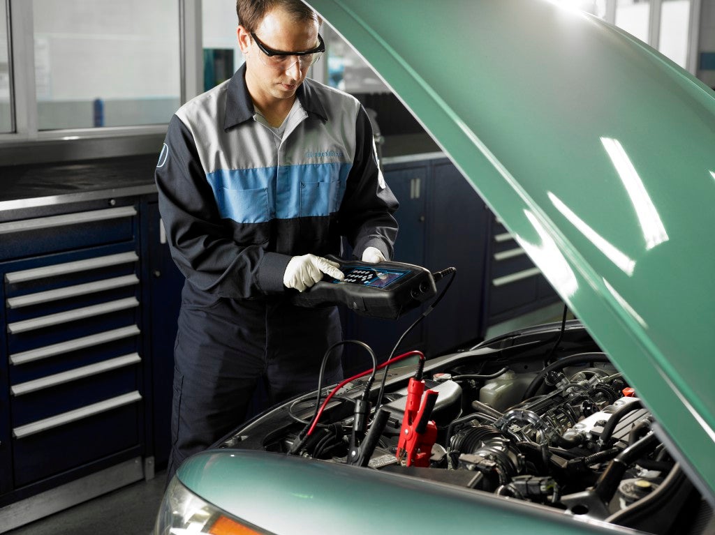 Automotive technician testing a vehicle battery with a digital conductance tester at Fremont Honda of Casper