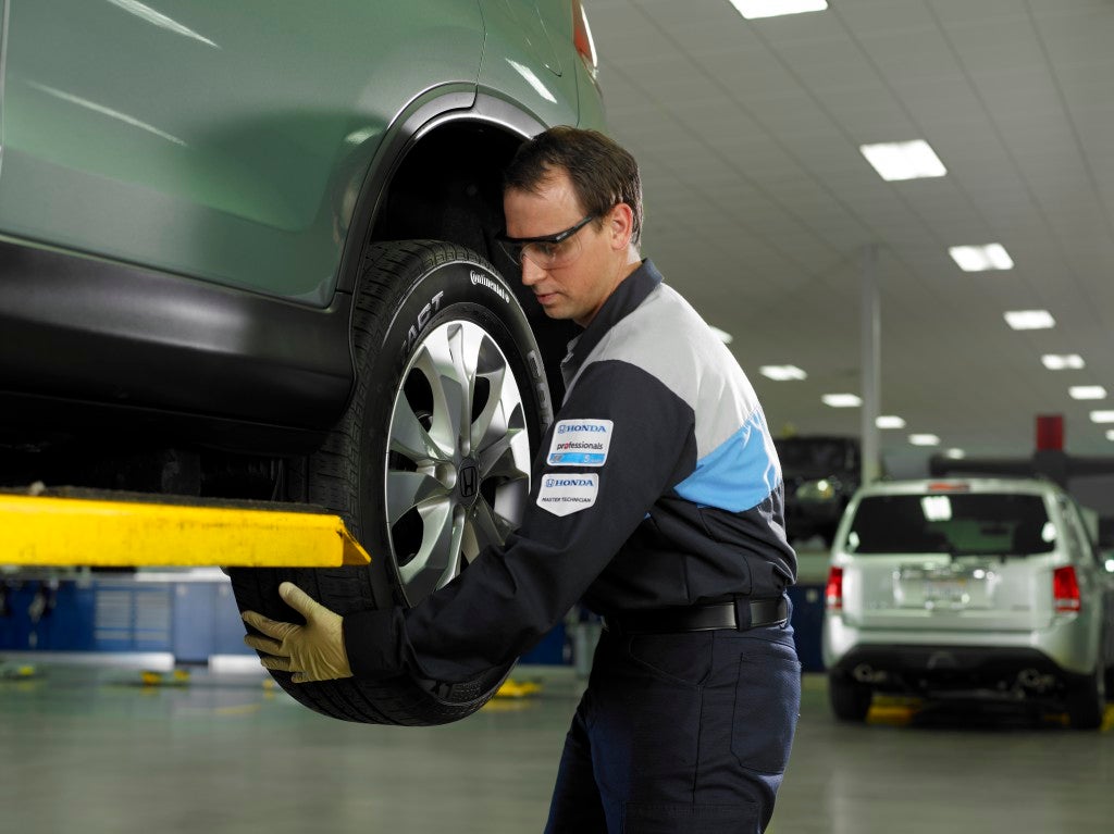 Certified automotive technician performing tire mounting and balancing service